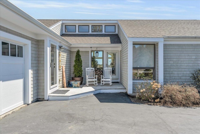 view of exterior entry featuring a porch and roof with shingles