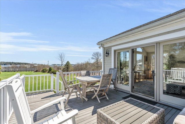wooden terrace featuring a lawn and outdoor dining space