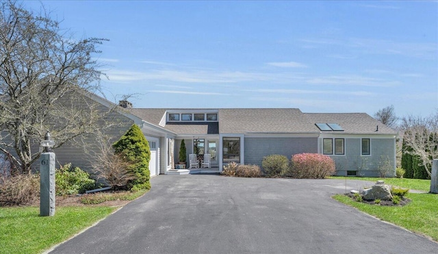 view of front facade with a garage, solar panels, and driveway