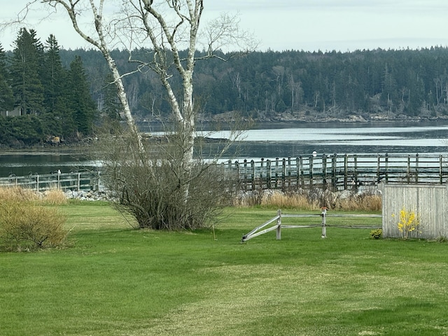 view of yard with a water view, fence, and a forest view