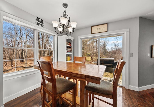 dining room featuring baseboards, a wealth of natural light, a notable chandelier, and wood finished floors