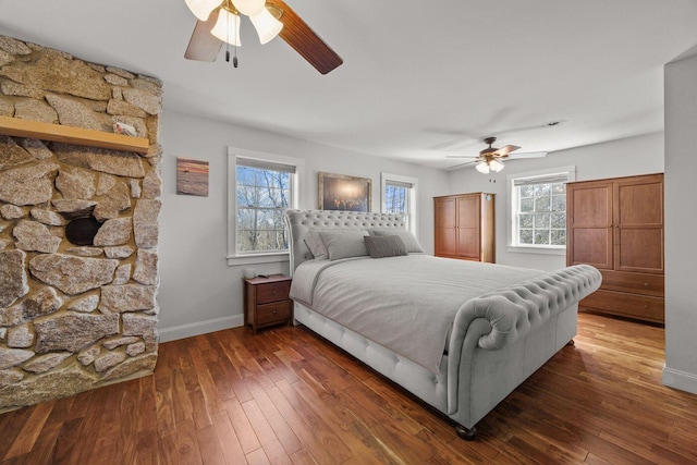 bedroom featuring ceiling fan, wood-type flooring, baseboards, and multiple windows