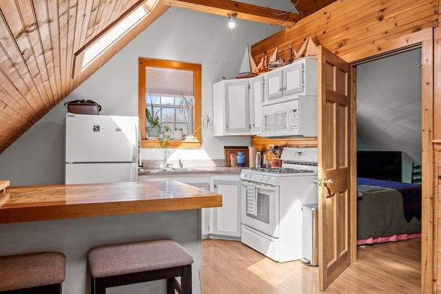 kitchen featuring lofted ceiling with skylight, a sink, white cabinets, light wood-type flooring, and white appliances