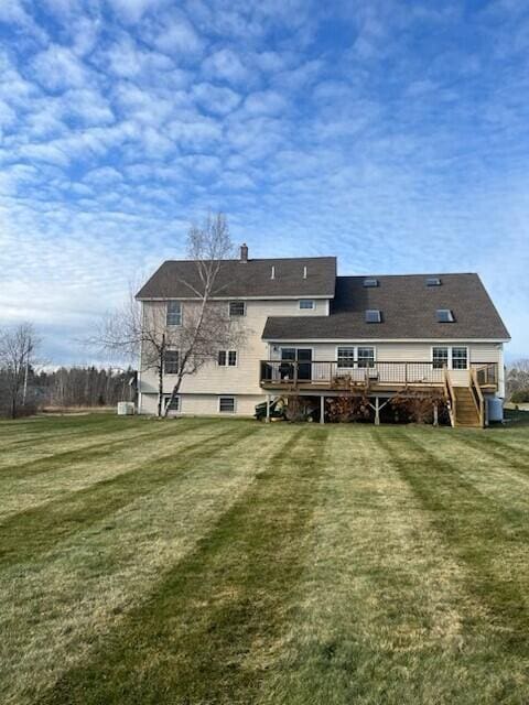 rear view of house featuring a lawn, a chimney, a deck, and stairway