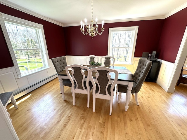 dining room featuring light wood-style floors, a baseboard radiator, wainscoting, and a chandelier