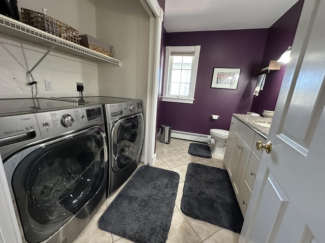 washroom featuring washer and dryer, laundry area, baseboard heating, baseboards, and light tile patterned floors