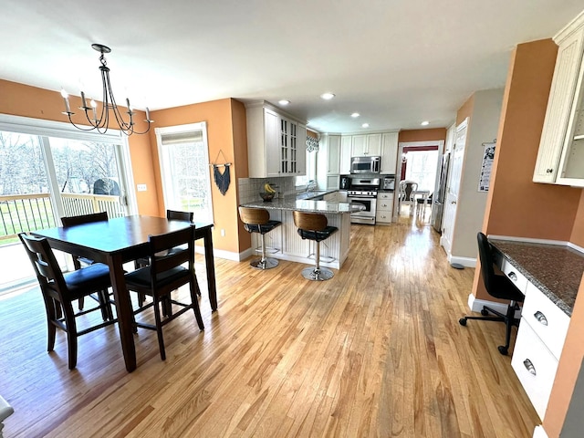 dining area with recessed lighting, baseboards, light wood finished floors, and a notable chandelier