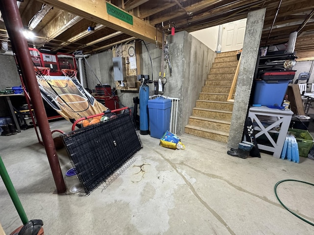 unfinished basement featuring stairs and electric panel