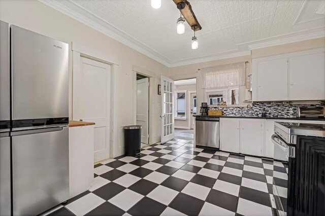 kitchen featuring dark floors, white cabinetry, ornamental molding, dark countertops, and appliances with stainless steel finishes