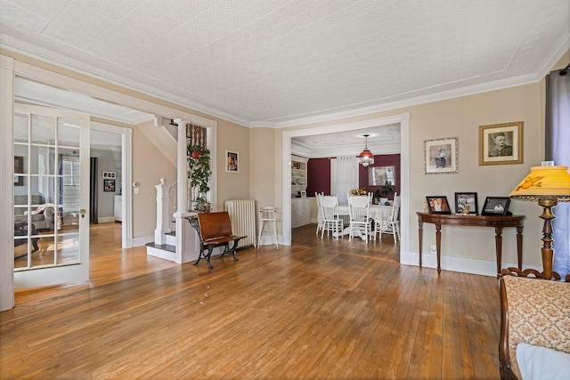 living area with baseboards, radiator heating unit, crown molding, and wood-type flooring
