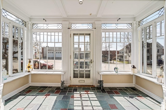 unfurnished sunroom featuring stone tile flooring, ornamental molding, and baseboards