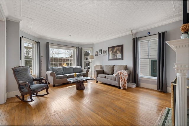 living room featuring baseboards, hardwood / wood-style flooring, and crown molding