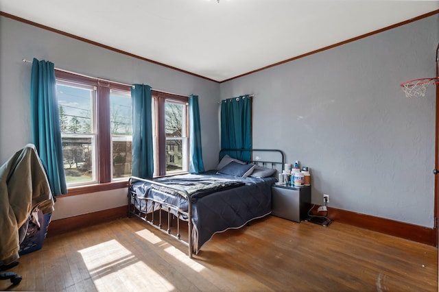 bedroom with baseboards, ornamental molding, and wood-type flooring