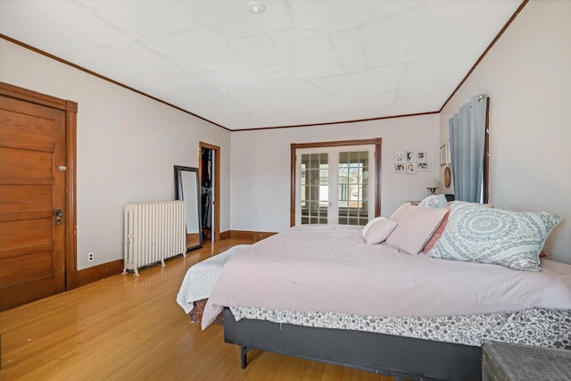 bedroom featuring baseboards, radiator, light wood-style floors, and crown molding