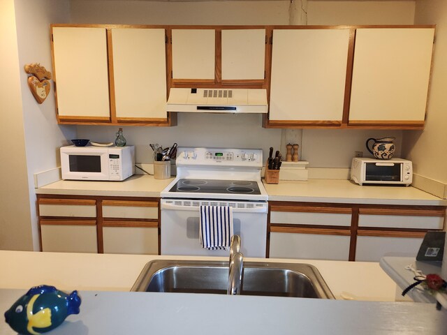kitchen with a toaster, white appliances, light countertops, under cabinet range hood, and a sink