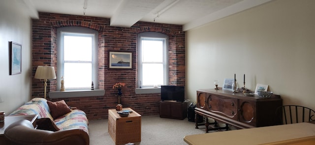 living area featuring beamed ceiling, carpet, and brick wall