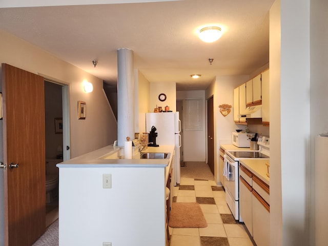 kitchen featuring a peninsula, white appliances, light countertops, under cabinet range hood, and light tile patterned floors