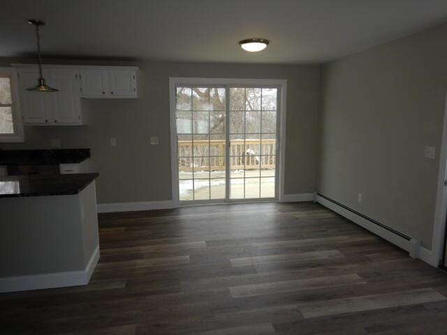 unfurnished dining area with a baseboard heating unit, a wealth of natural light, and baseboards