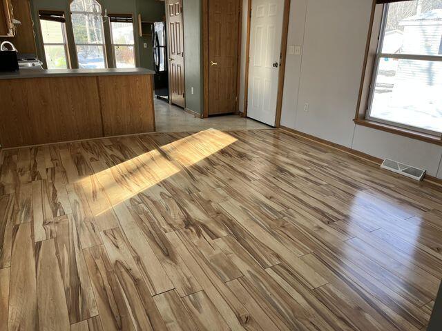 empty room featuring visible vents, light wood-type flooring, and a healthy amount of sunlight
