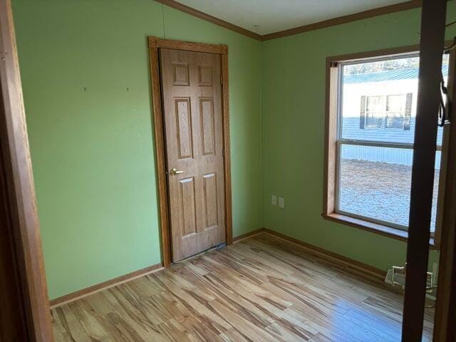 unfurnished bedroom with baseboards, ornamental molding, and light wood-style flooring