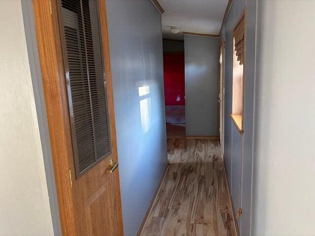 corridor with wood finished floors and crown molding