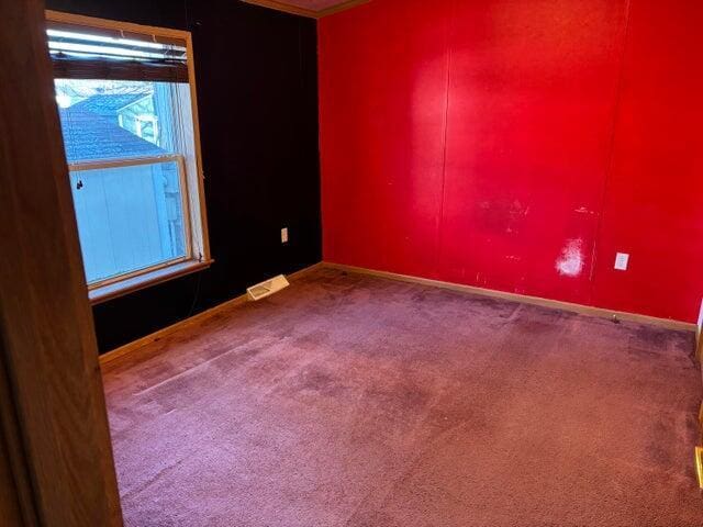 carpeted spare room with visible vents and baseboards