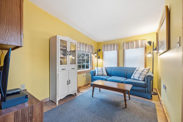 living room with light wood-style floors, vaulted ceiling, baseboards, and an office area