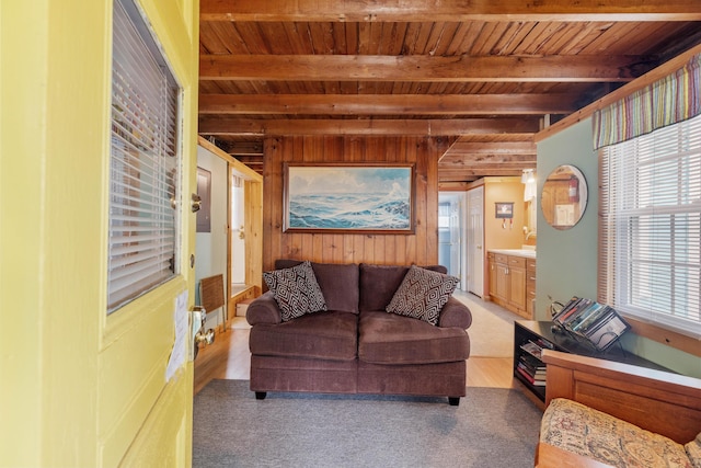 living area featuring wood walls, wood ceiling, light wood finished floors, and beamed ceiling