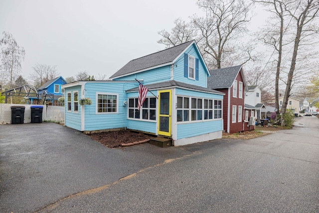 view of front of property featuring roof with shingles, a sunroom, and driveway