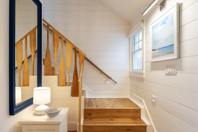 stairway with wood finished floors and lofted ceiling
