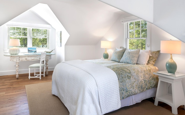 bedroom featuring baseboards, wood finished floors, and vaulted ceiling