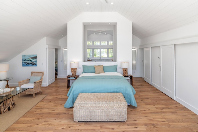 bedroom featuring baseboards, light wood-style flooring, and lofted ceiling