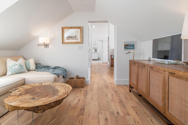 living area with baseboards, vaulted ceiling, and light wood-style floors