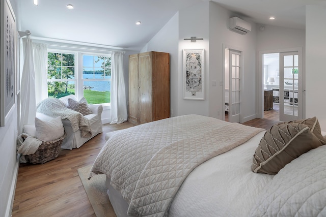 bedroom featuring recessed lighting, a water view, lofted ceiling, an AC wall unit, and wood finished floors