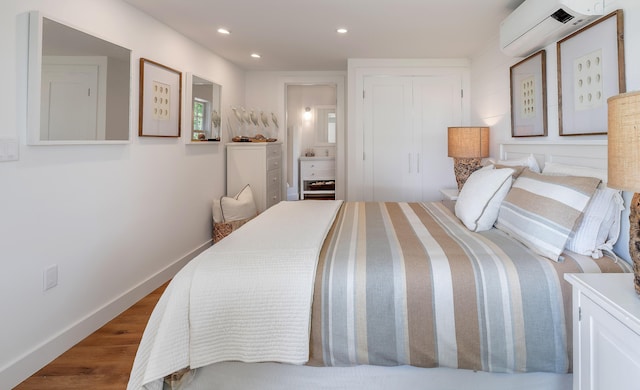 bedroom featuring recessed lighting, a wall mounted AC, a closet, baseboards, and wood finished floors