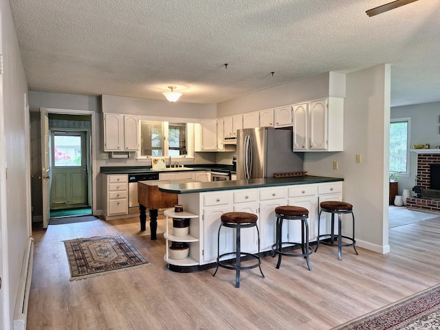 31 Arbor Ave, Topsham, ME 04086 - kitchen featuring stainless steel appliances, dark countertops, a peninsula, a textured ceiling, and light wood-style flooring
