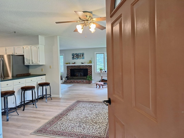 31 Arbor Ave, Topsham, ME 04086 - kitchen with light wood-type flooring, dark countertops, white cabinets, a ceiling fan, and a fireplace