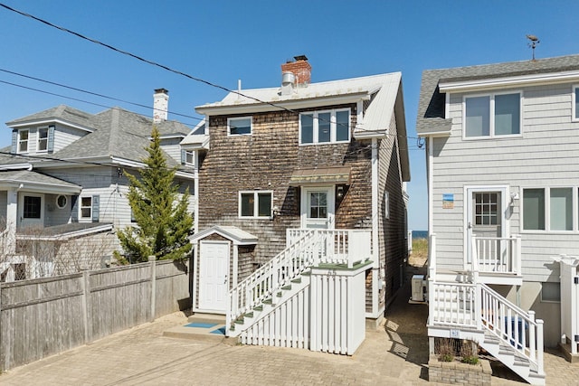 rear view of property with stairs, fence, a chimney, and a patio