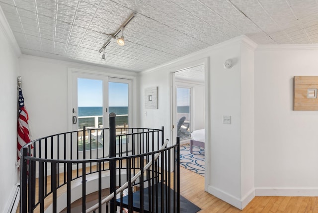 dining space featuring an ornate ceiling, ornamental molding, a water view, and light wood-type flooring