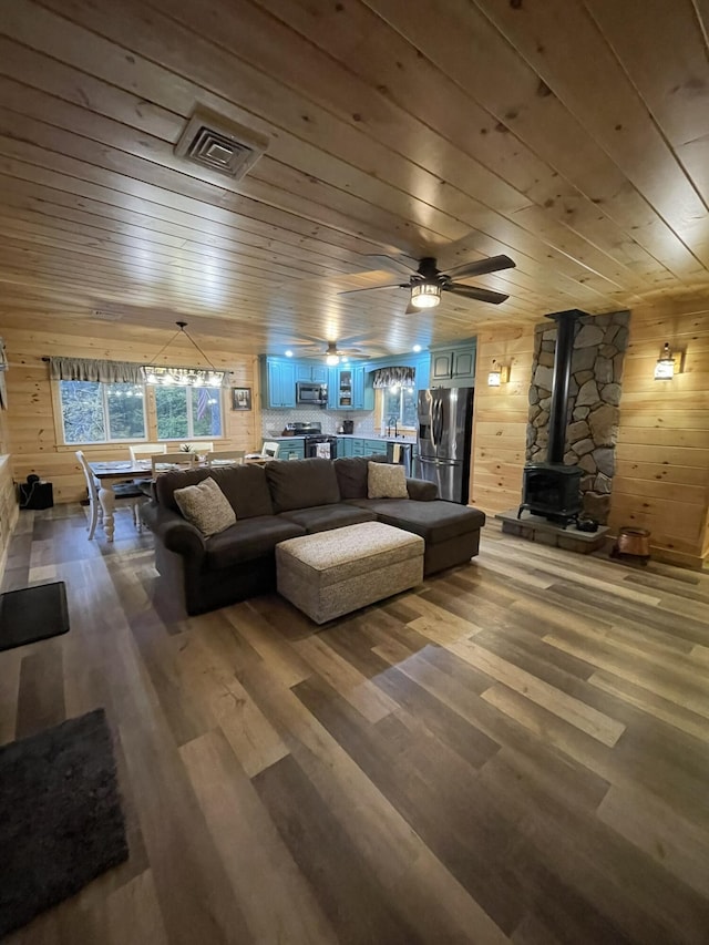 137 Maplewood Dr, Naples, ME 04055 - living area with a wood stove, wooden ceiling, wood walls, wood finished floors, and ceiling fan