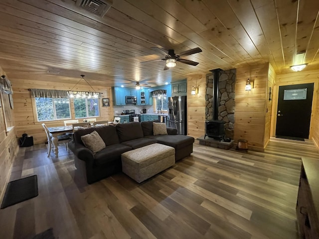 137 Maplewood Dr, Naples, ME 04055 - living room featuring a wood stove, wooden ceiling, wood walls, wood finished floors, and a ceiling fan