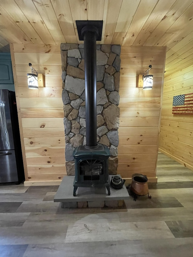137 Maplewood Dr, Naples, ME 04055 - detailed view of freestanding refrigerator, a wood stove, wooden ceiling, wooden walls, and wood finished floors