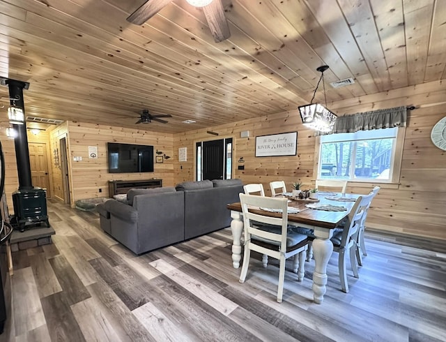 137 Maplewood Dr, Naples, ME 04055 - dining area featuring a ceiling fan, wood walls, a wood stove, wooden ceiling, and wood finished floors