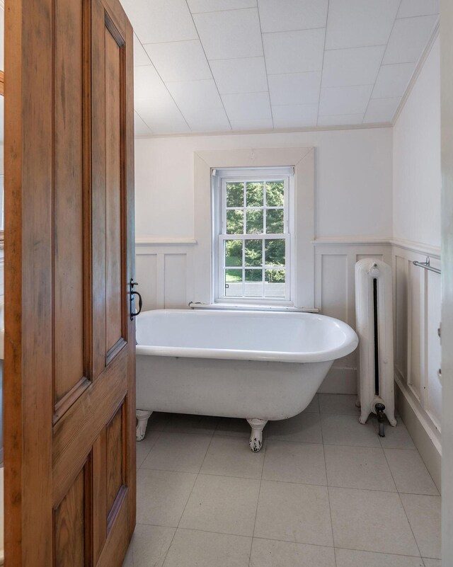 258 River Rd, Eliot, ME 03903 - bathroom featuring tile patterned flooring, radiator, wainscoting, a decorative wall, and a freestanding bath