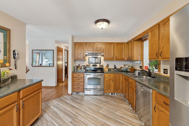 171 Regan Ln, Portland, ME 04103 - kitchen featuring appliances with stainless steel finishes, a sink, under cabinet range hood, dark countertops, and brown cabinets