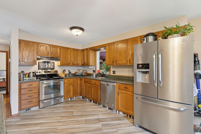 171 Regan Ln, Portland, ME 04103 - kitchen featuring appliances with stainless steel finishes, under cabinet range hood, dark countertops, a sink, and brown cabinetry
