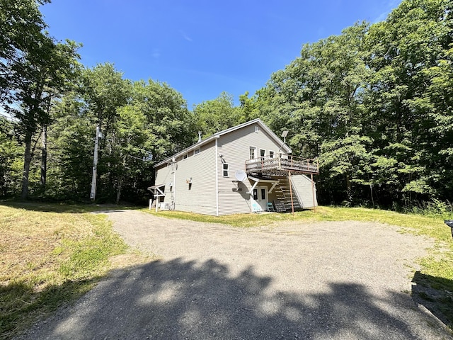 1057 Back Brooks Rd, Monroe, ME 04951 - view of side of property with gravel driveway, a deck, a view of trees, and a yard