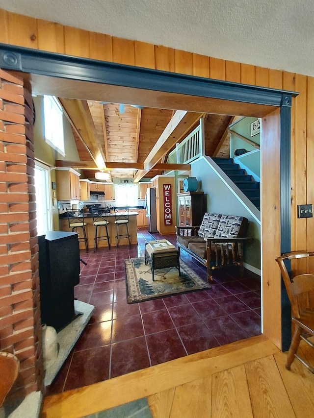 372 Pine Springs Rd, Shapleigh, ME 04076 - living room with dark tile patterned floors, a wood stove, stairway, and beamed ceiling