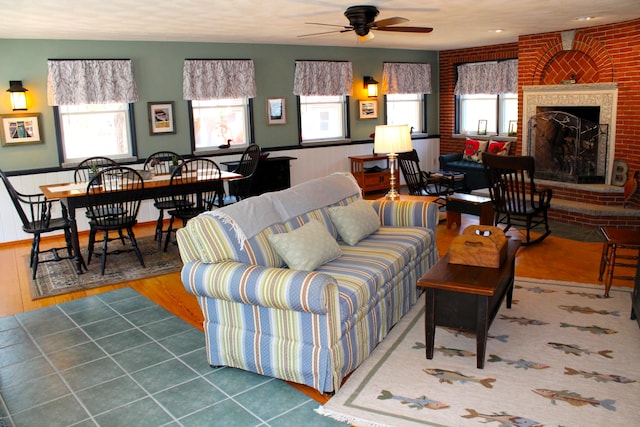 372 Pine Springs Rd, Shapleigh, ME 04076 - living room with a ceiling fan, wainscoting, a brick fireplace, and wood finished floors