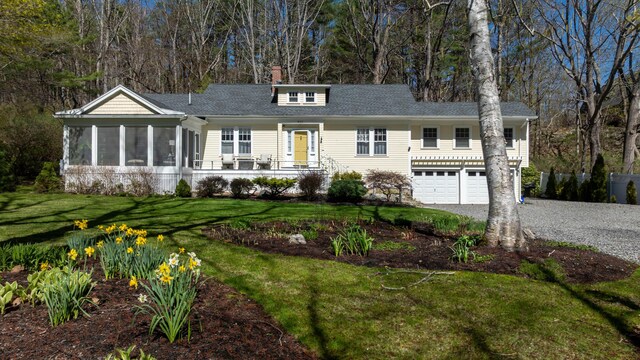 single story home featuring a garage, a front yard, gravel driveway, roof with shingles, and a sunroom
